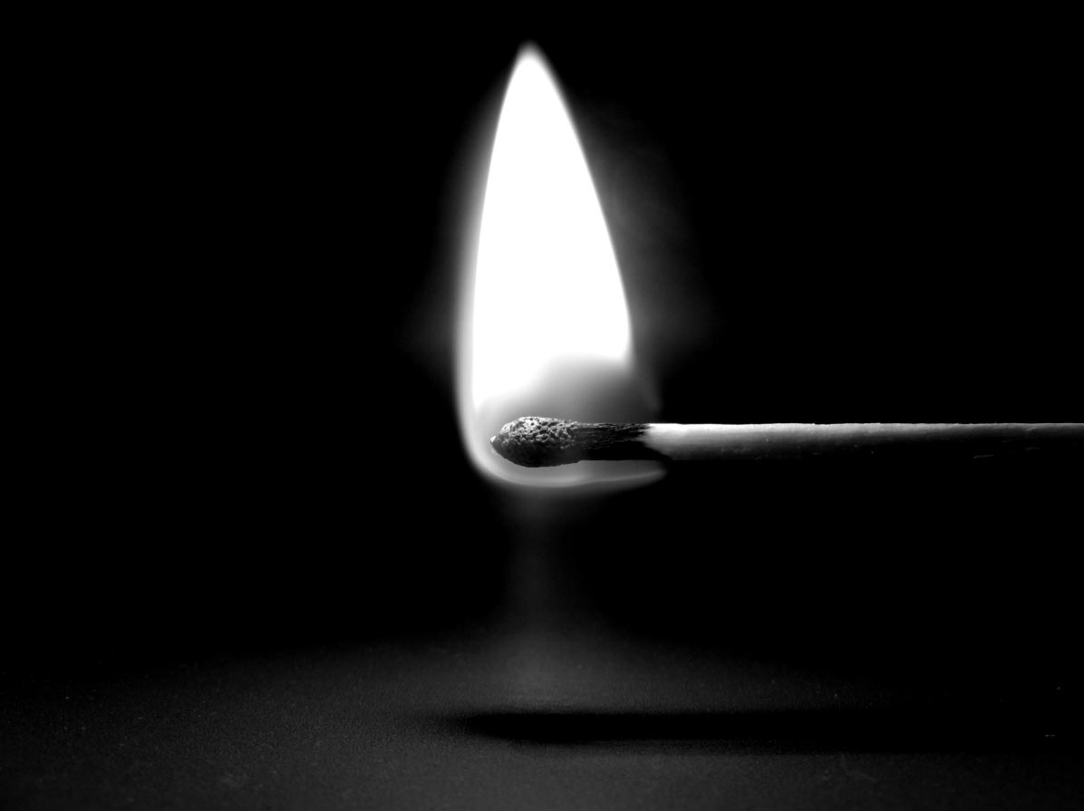 Photo en noir et blanc d'une allumette en feu.